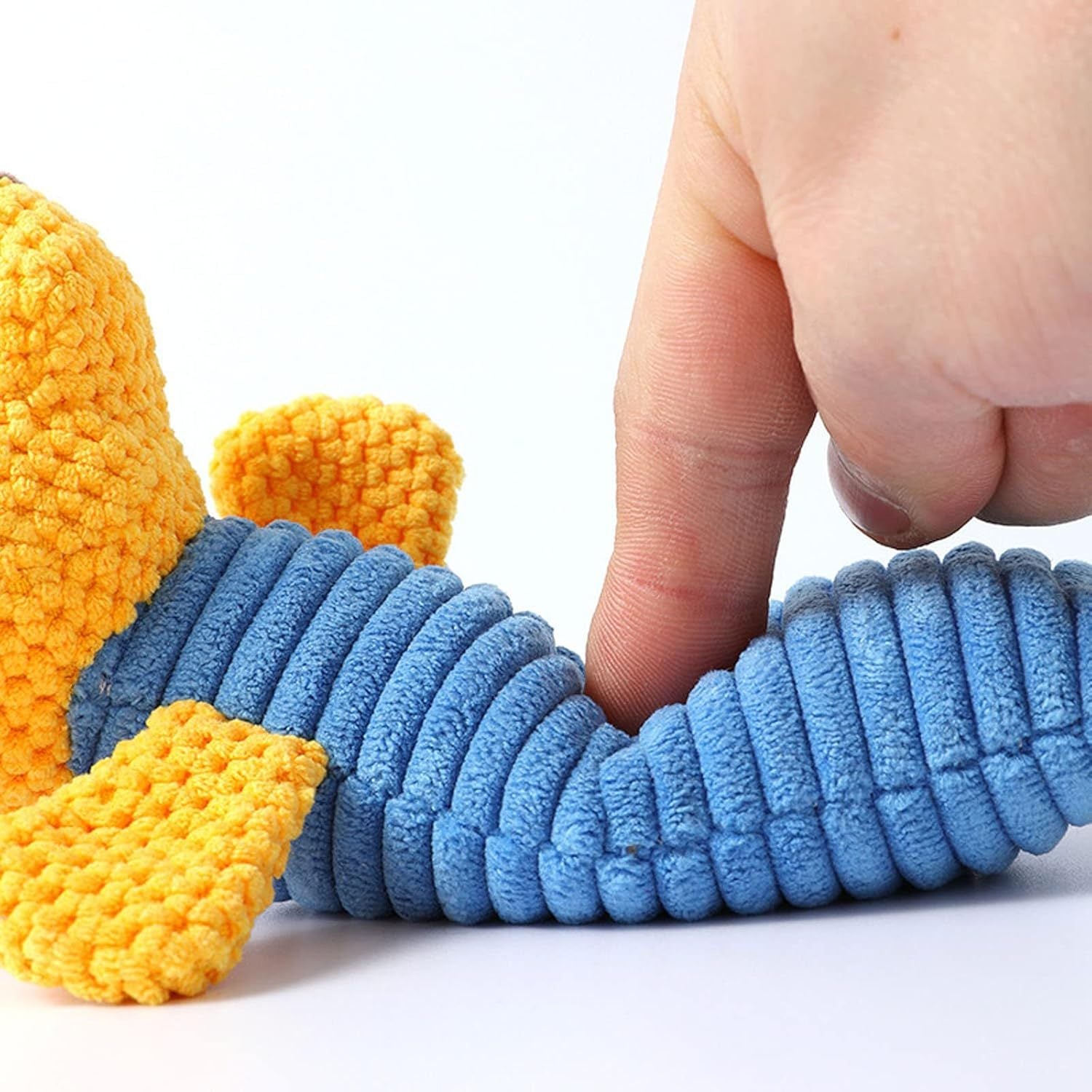 Blue and yellow squeaky dog toy showing soft plush material being pressed